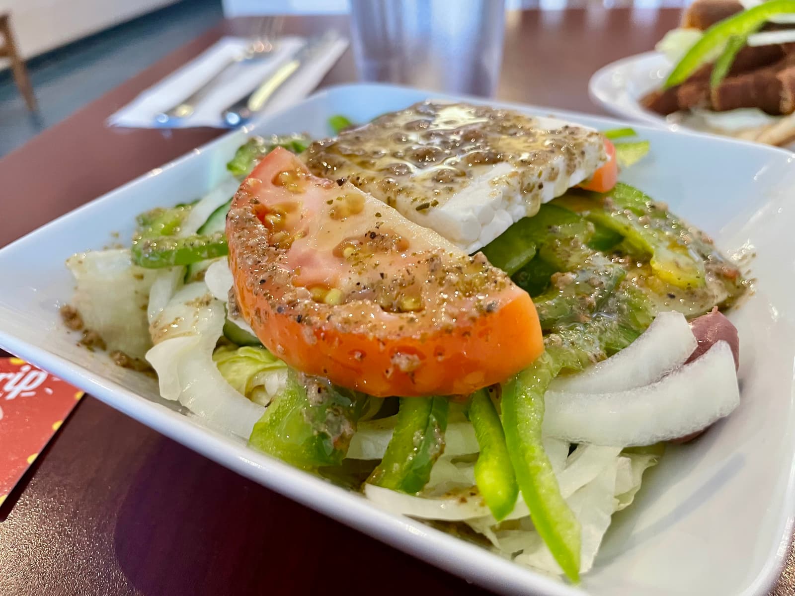 A fresh, crunchy Greek salad dressed with olive oil and topped with a generous block of feta to kick things off