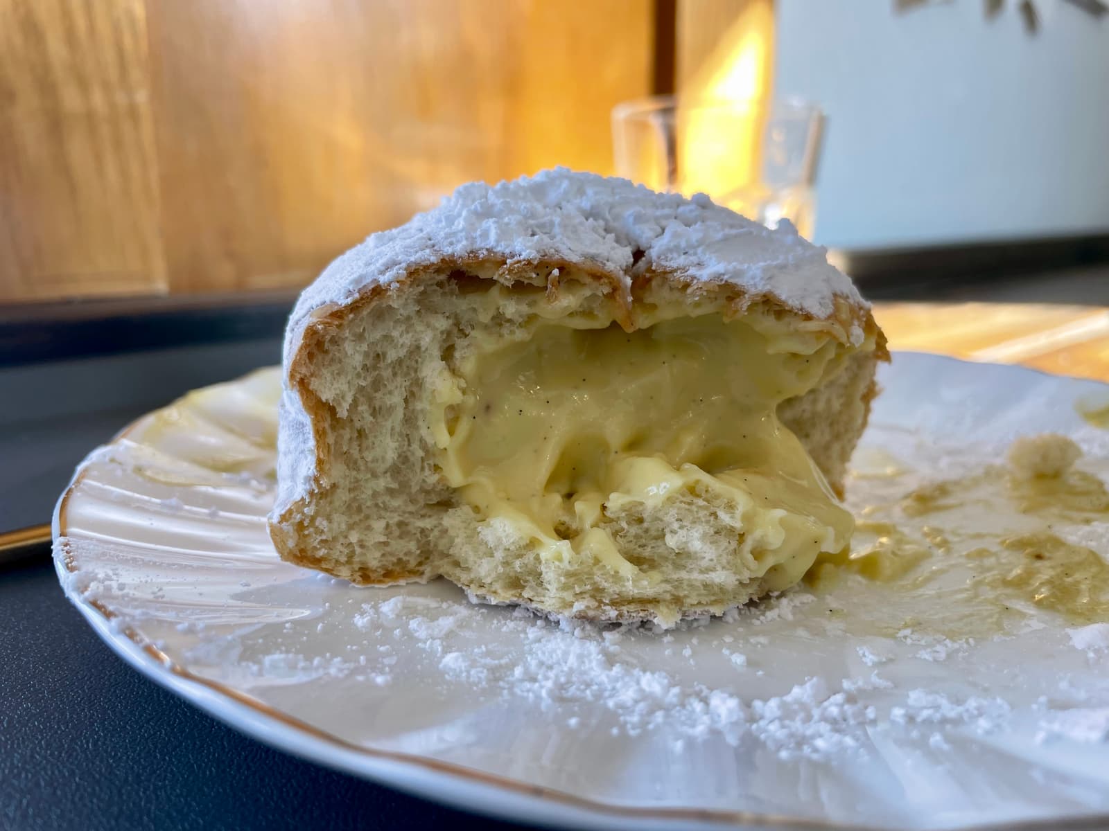 A sugar-dusted bombolone filled with silky custard—proof that simplicity, when done right, is pure perfection