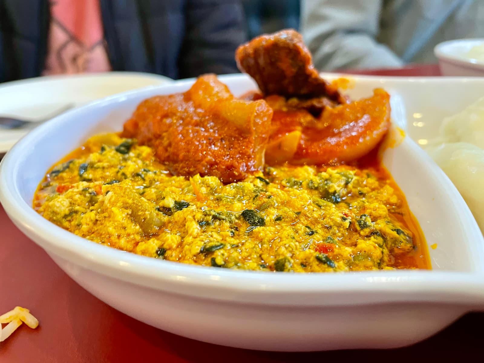 Egusi soup served with pillowy fufu and generous pieces of richly seasoned goat and traditional meats