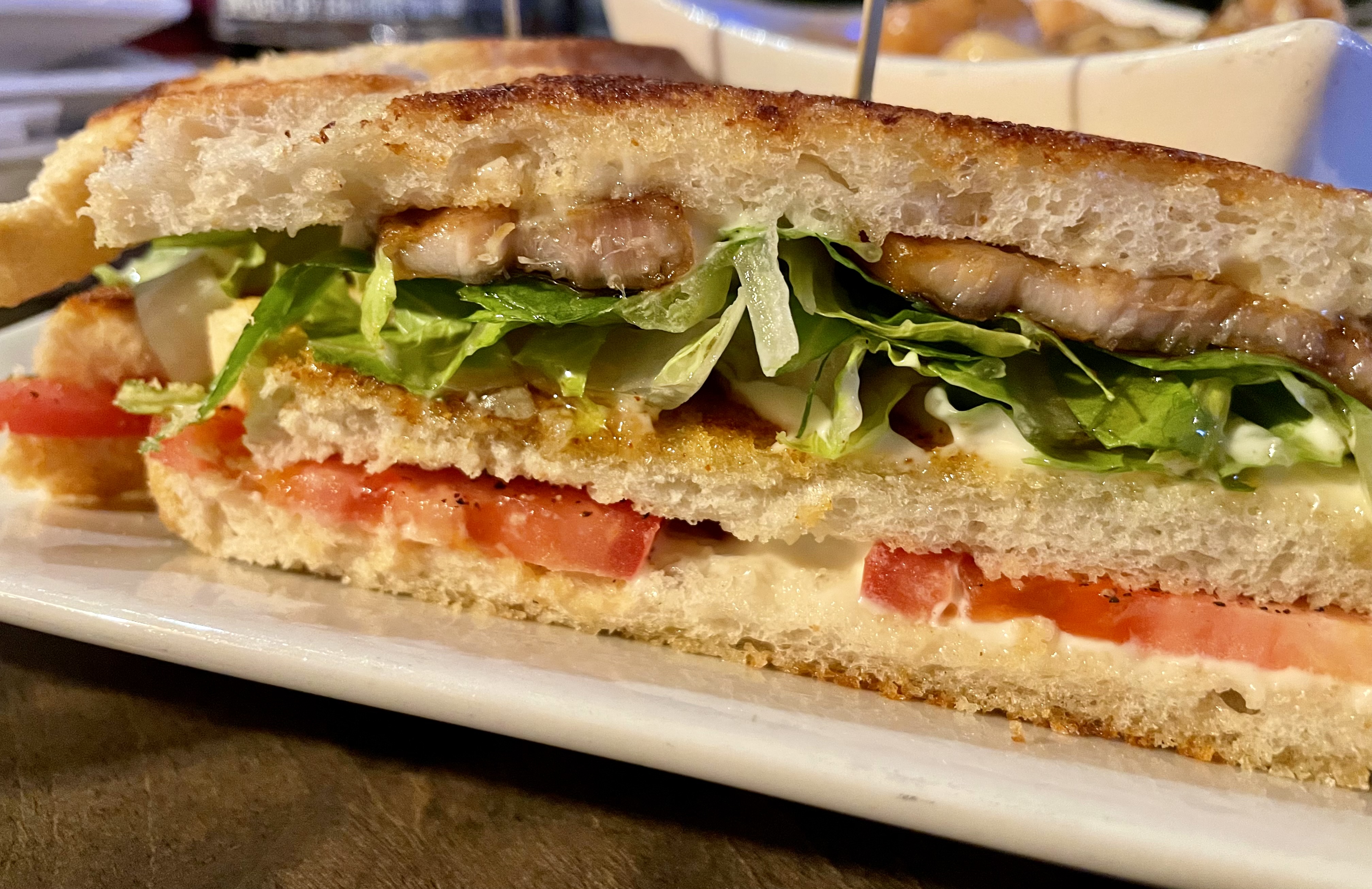 The porkbelly clubhouse sandwich comes with house roasted sliced chicken, crispy pork belly, lettuce, tomato, aioli on toasted and buttered bread from the Portuguese bakery