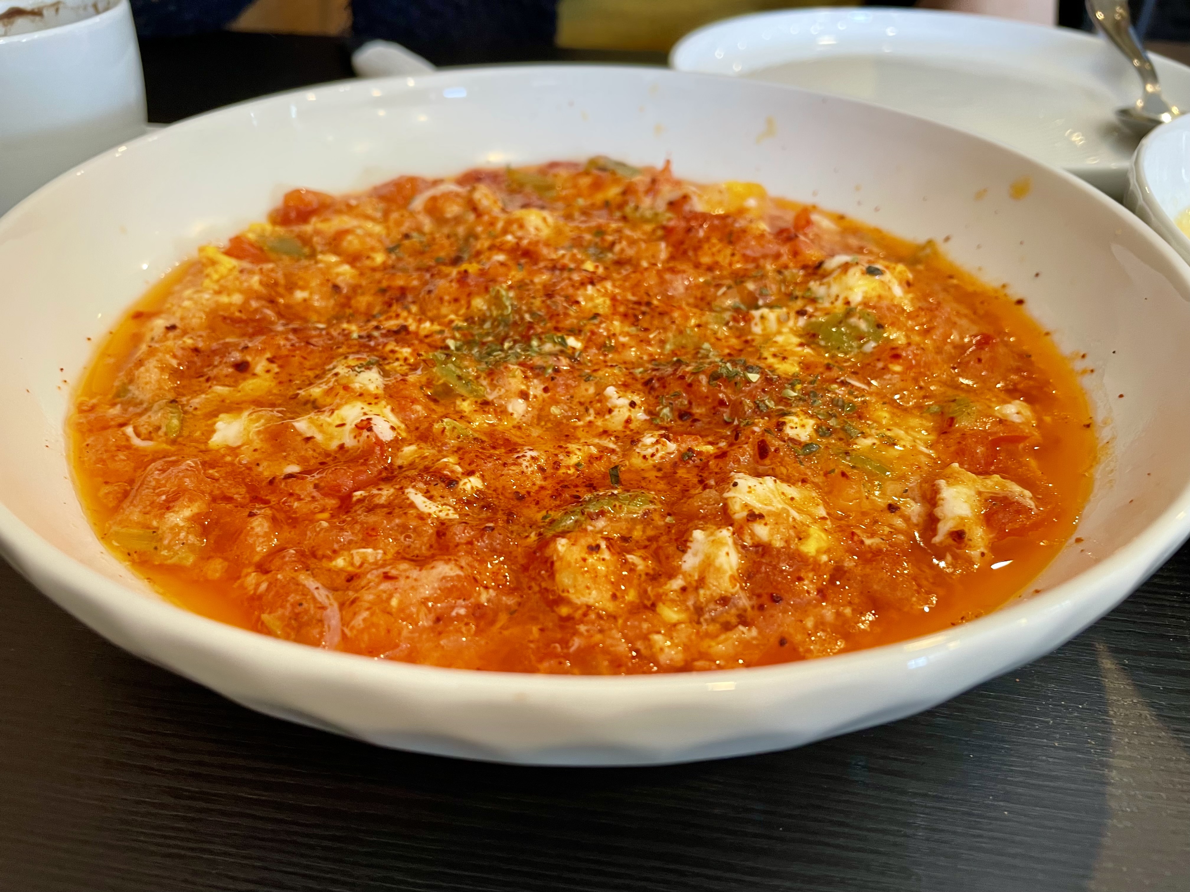Menemen is a popular Turkish dish that includes eggs, tomato, green peppers and spices such as ground black and red pepper cooked in olive oil