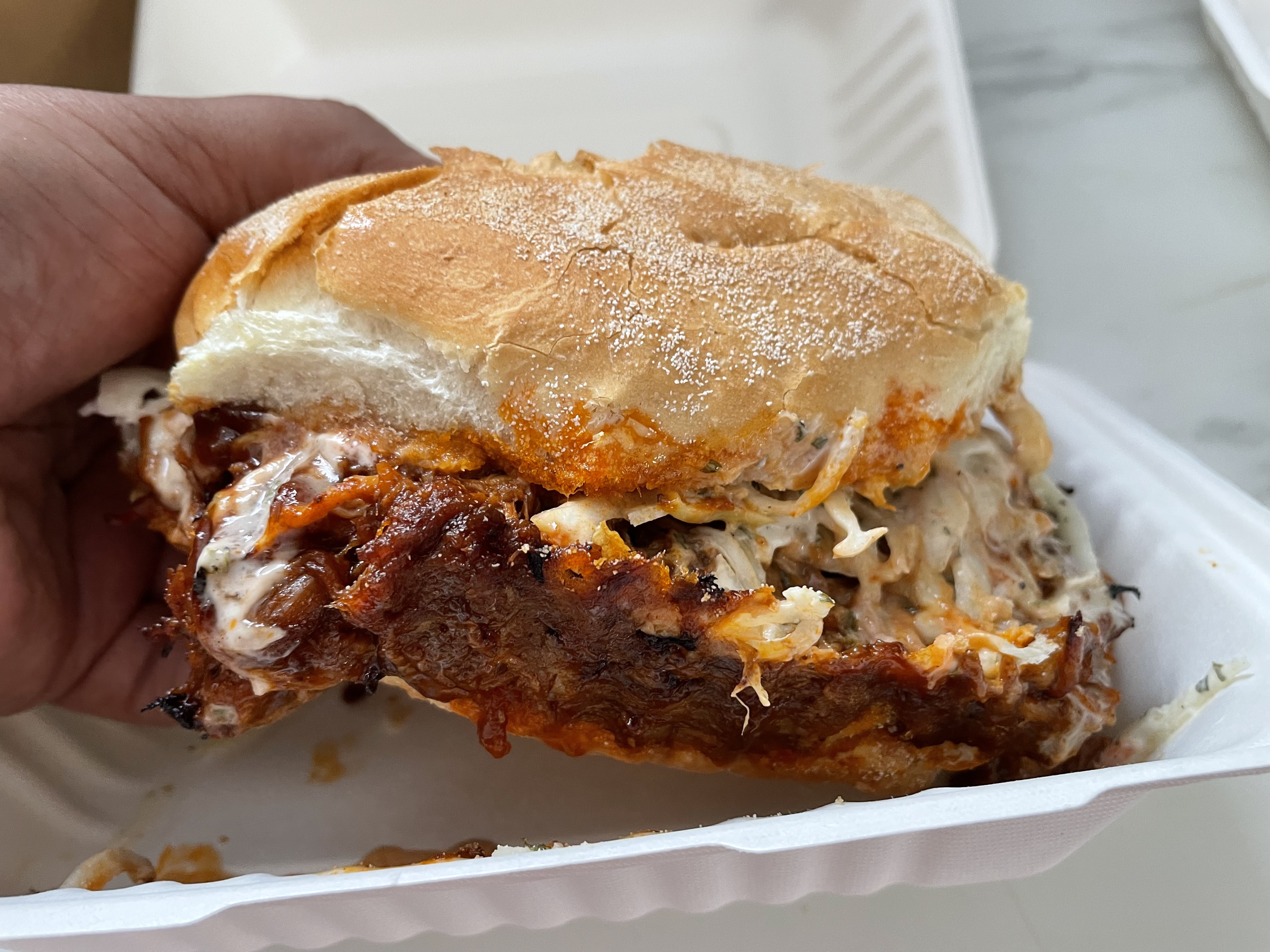 Danielle tackles The Sandwich Stop's The Pig sandwich, featuring sweet and abundant meat piled high on a fresh Kaiser roll - a portion so generous it challenges the laws of physics and appetite