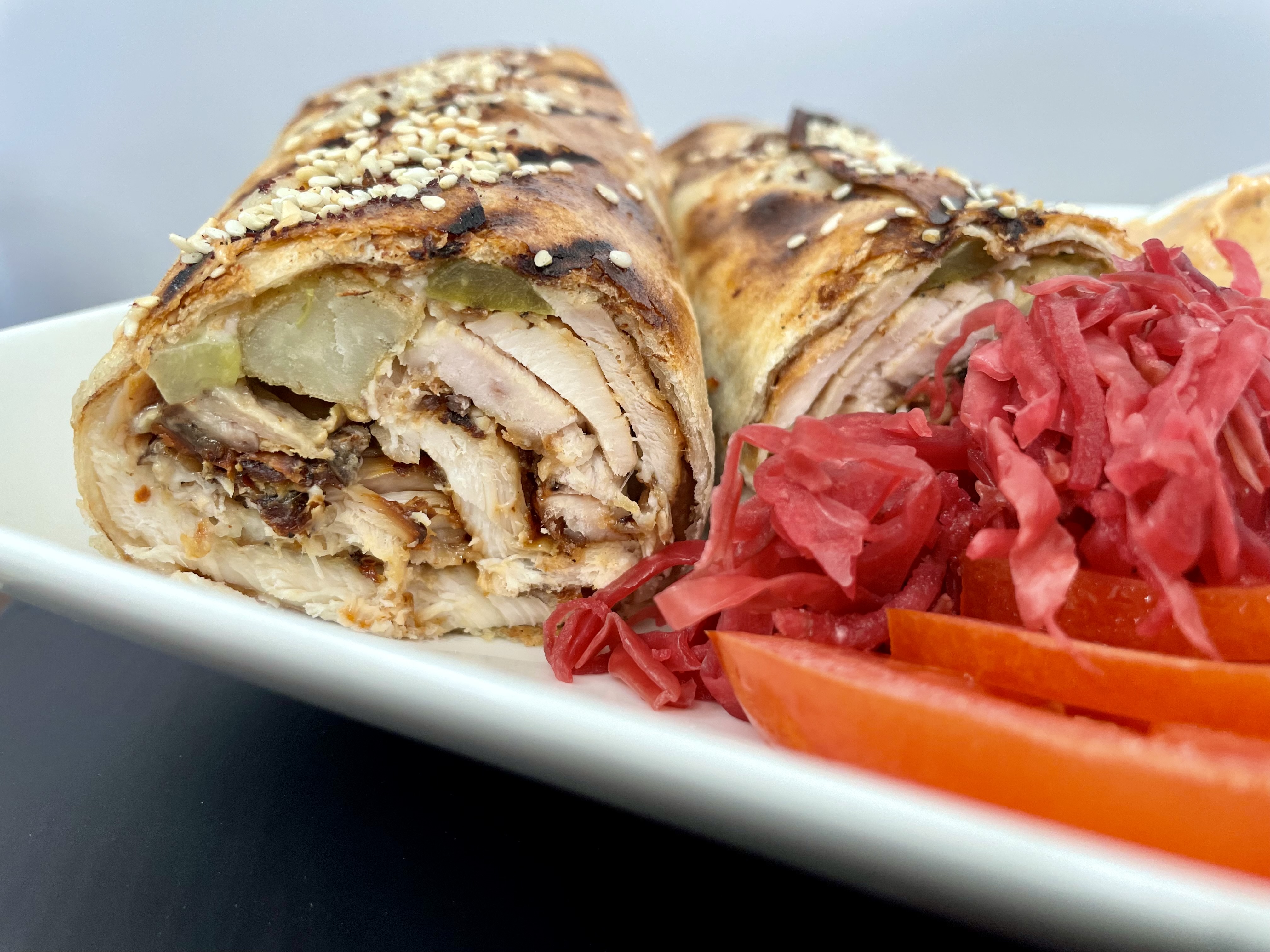 A fresh-off-the-grill chicken saj wrap, packed with crisp veggies, house-made garlic sauce, and sizzling shawarma, wrapped in warm, chewy saj bread