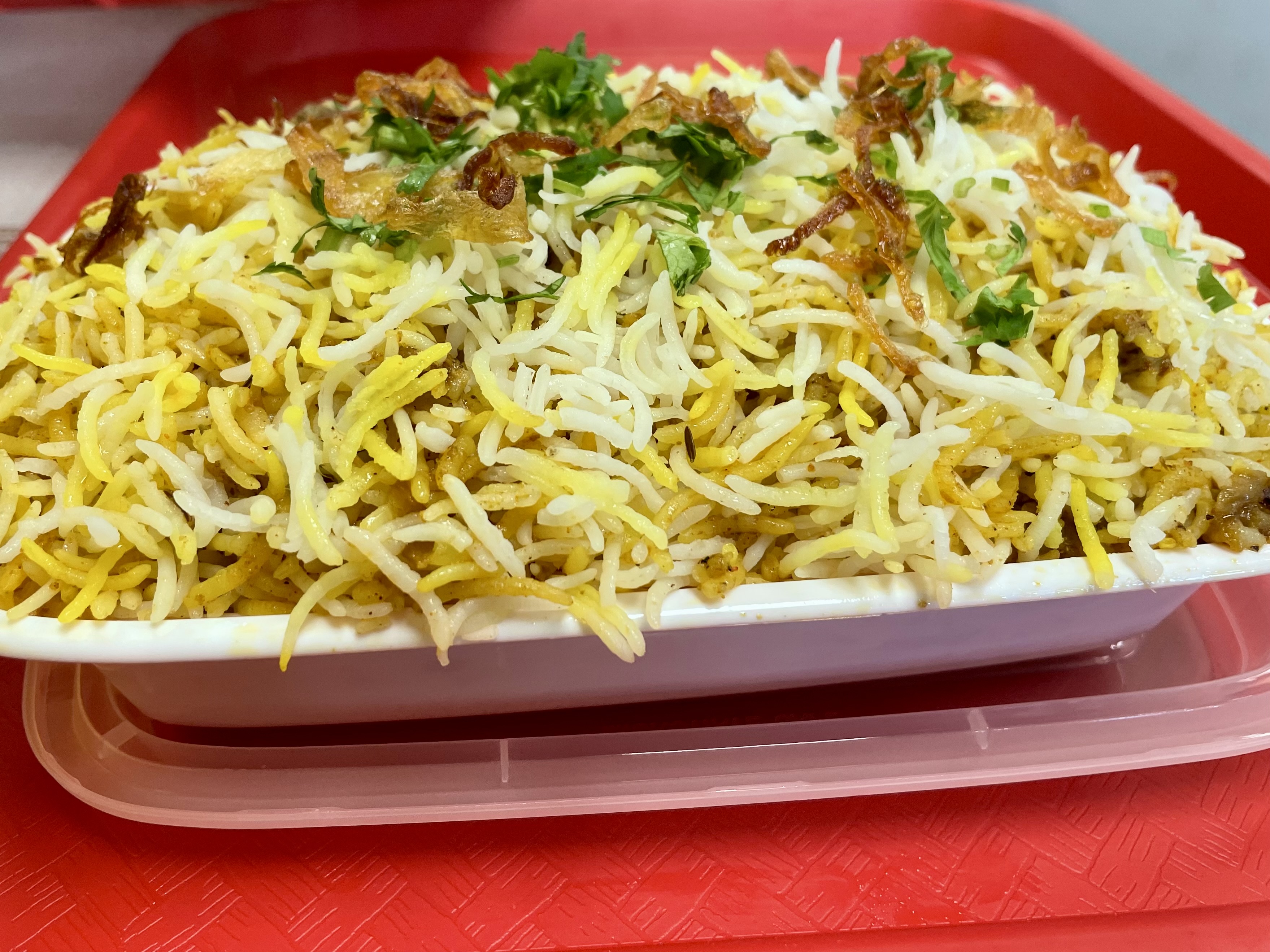 A mound of fragrant basmati rice hides fall-apart mutton in this slow-cooked biryani, topped with crispy fried onions and served with a side of raita.