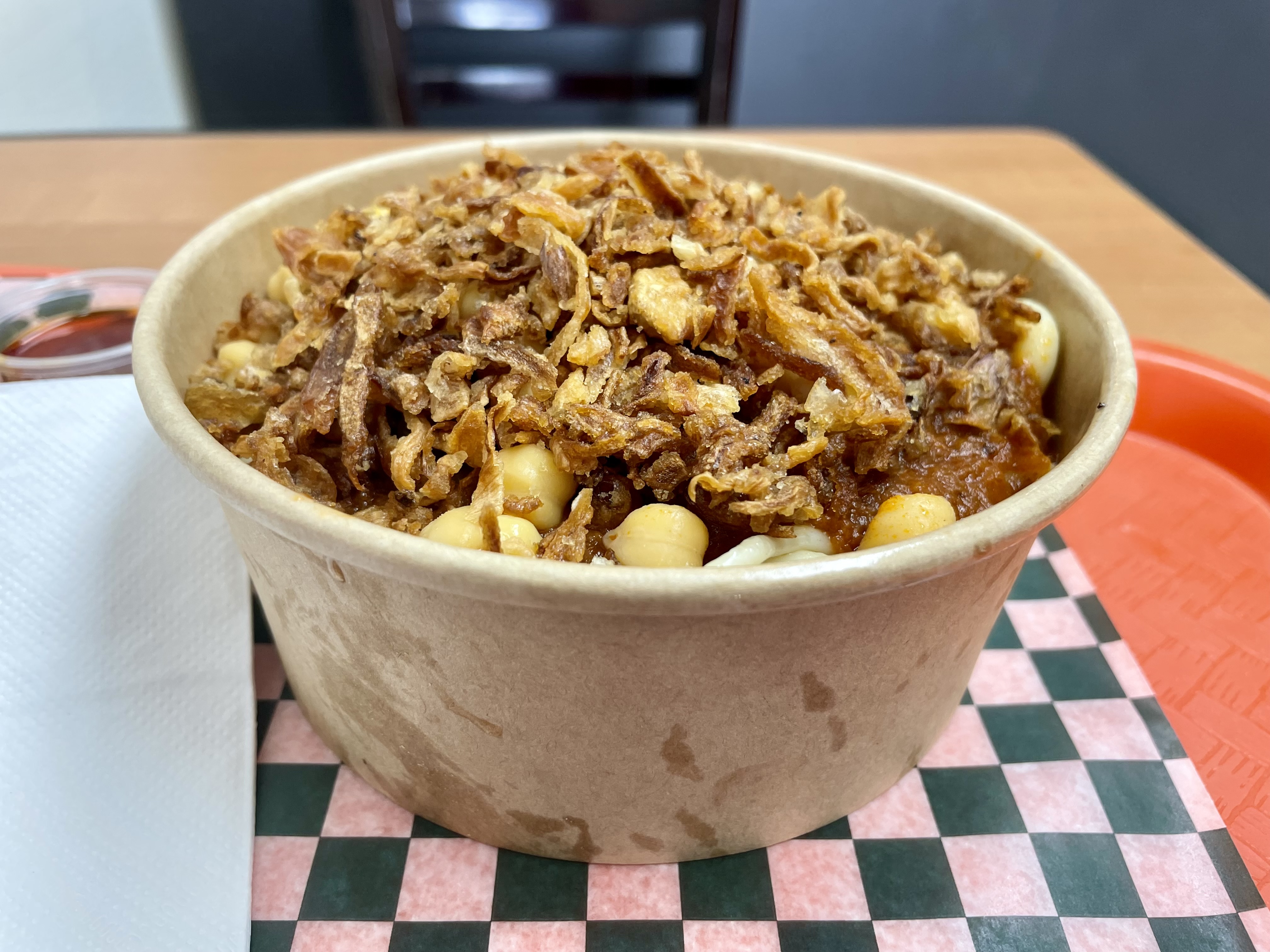 A hearty street food staple from Egypt, this koshari is piled high with pasta, lentils, chickpeas, and fried onions—and served with two bold house-made sauces